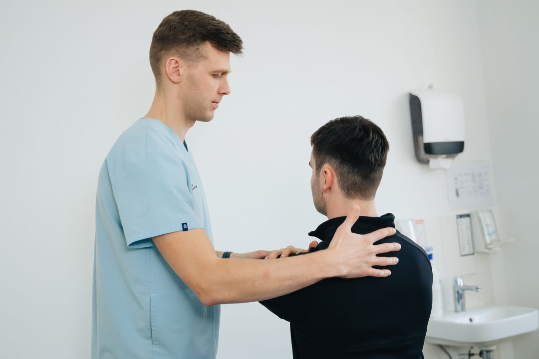 Physiotherapist assessing a patient’s shoulder in a bright clinic