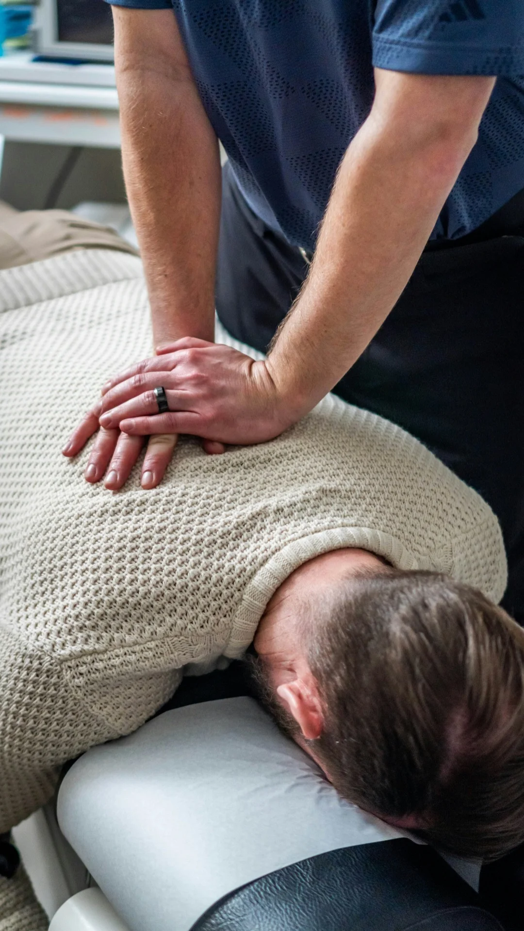 Therapist assessing a patient’s upper back and neck