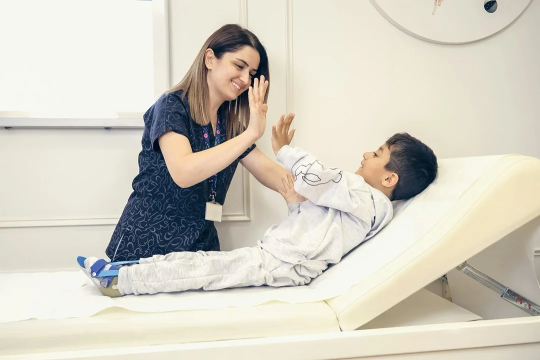 A therapist sharing a high-five with a young patient during a clinic visit