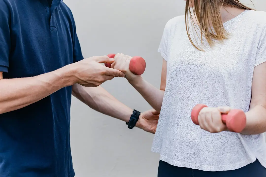 Practitioner guiding a patient through a strengthening exercise with hand weights