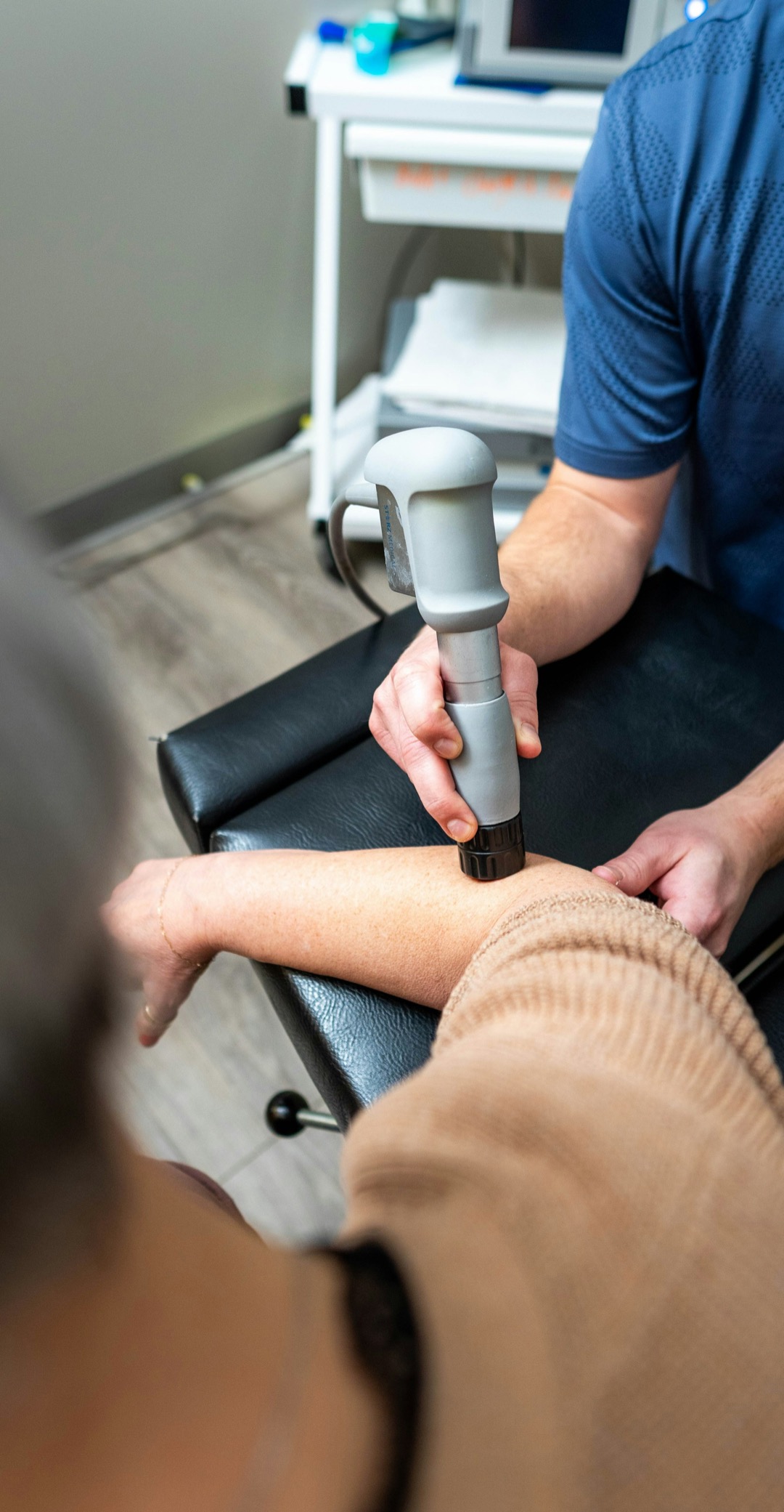 Therapist applying a shockwave therapy device to a patient’s arm