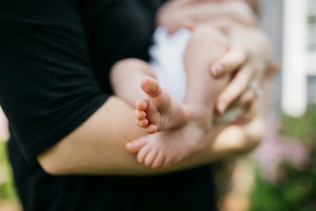A parent gently holding their baby, representing postnatal care